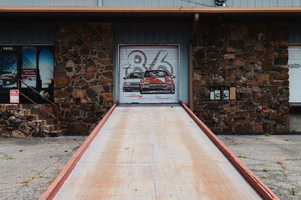 A ramp up to a garage door with old Toyotas painted on it. 