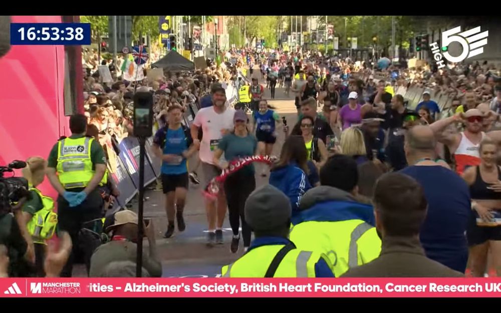 Humphrey crossing the finish line in white T shirt with all the runners in the background