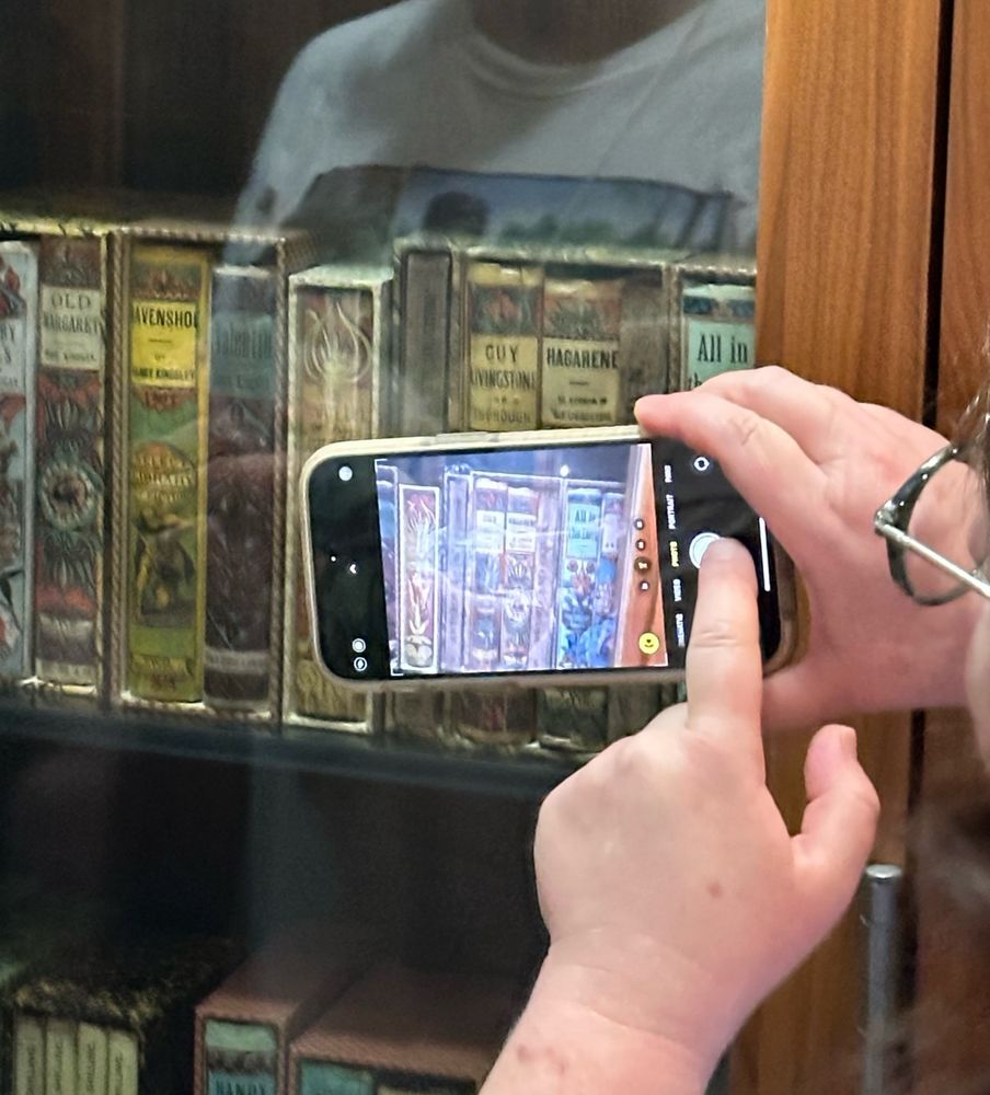 A person taking a picture of old books on a shelf