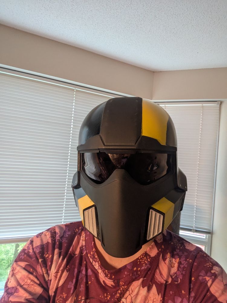 A picture of me wearing a Helldivers 2 cosplay helmet. 3D printed plastic and hand painted by me.