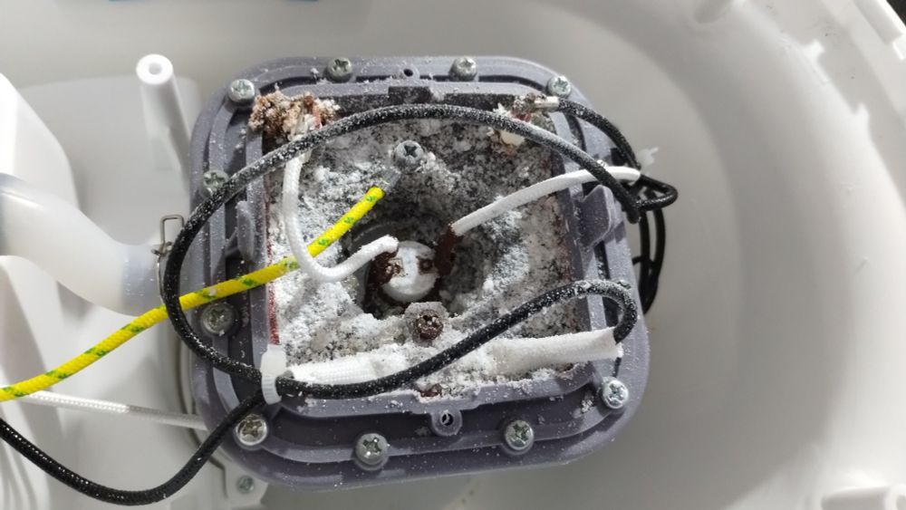 Lower side of the heating element from a garment steamer, the seal shows damage and the metal is rusted and has a calcium buildup