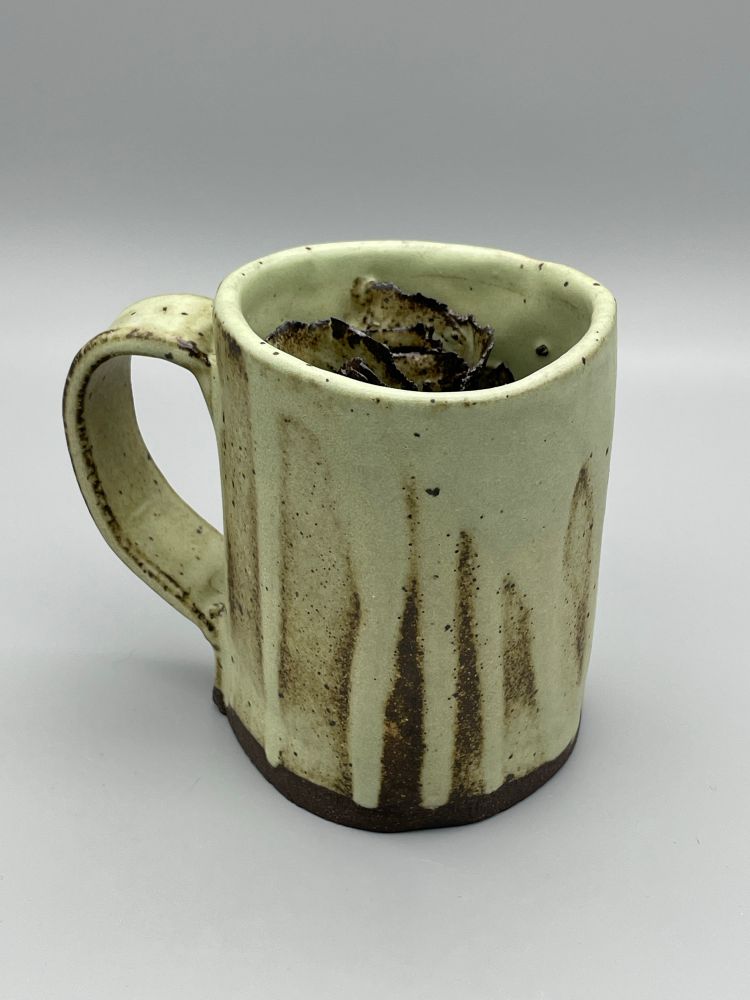 A dark stoneware mug with a minty green matte glaze.