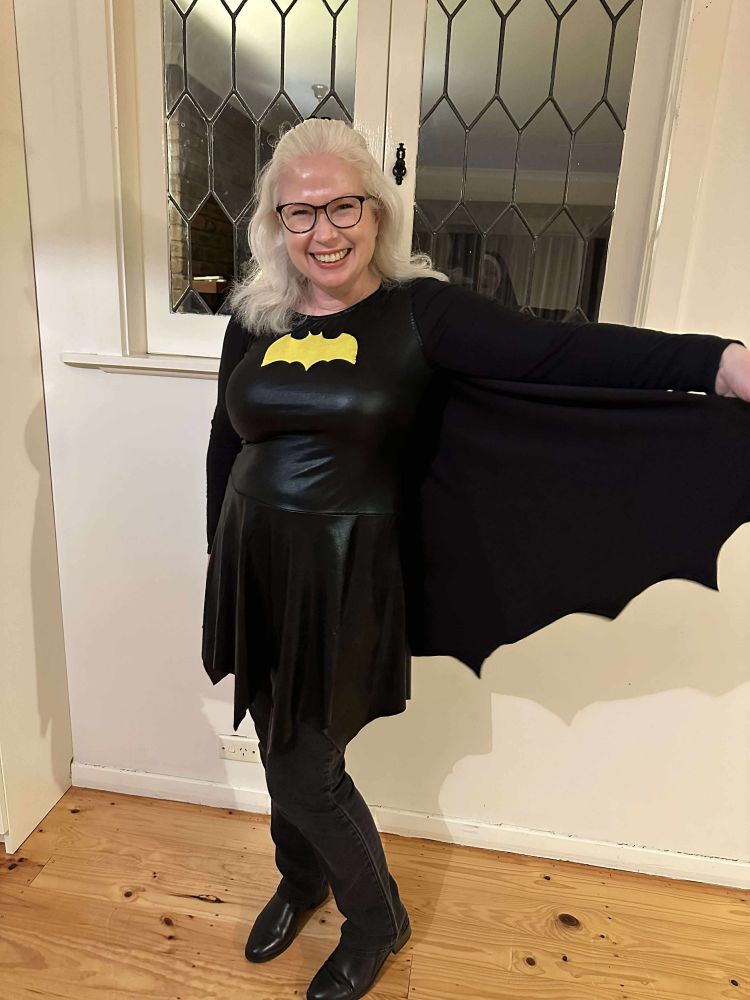 Author Cassandra O'Leary dressed in a black Batgirl costume at a romance writers retreat.