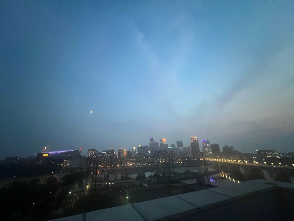Hazy wildfire smoke filled sky at sunset facing downtown Minneapolis from the east bank. 