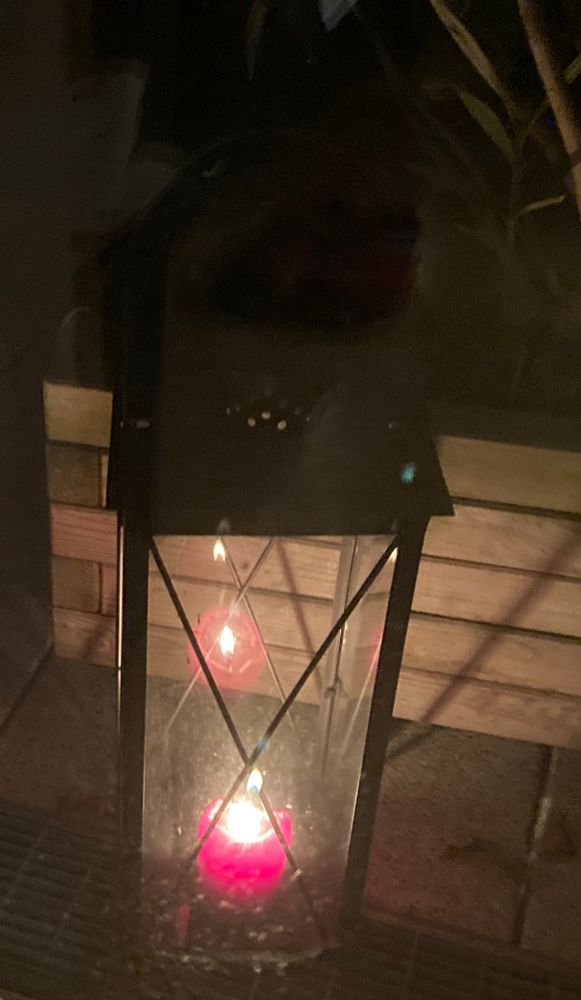 Eine große Laterne mit einer roten, brennenden Kerze.