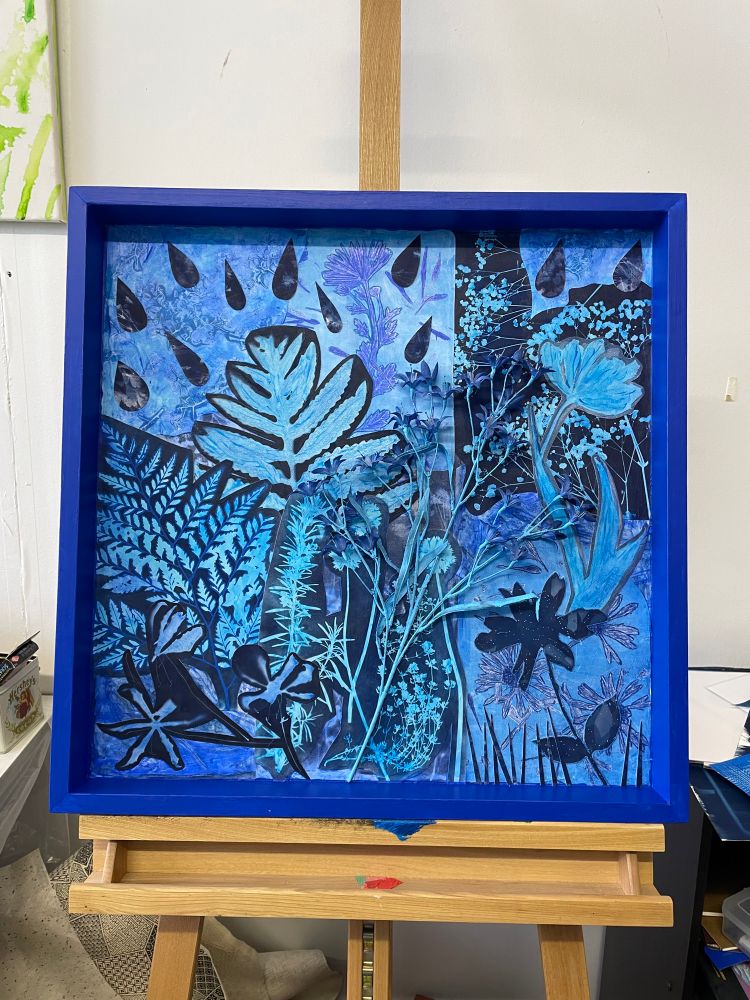 A 24” square piece of art in different shades of blue with various botanical elements 
