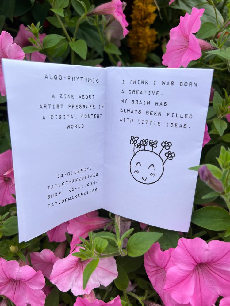 I did front cover and page one of the zine. Inside cover reads "Algo-Rhythmic A zine about artist pressure in a digital content world." End text. Inside page also lists the artist's Ko-Fi, Instagram, and BlueSky, which are all Taylor Makes Zines

Page two reads "I think I was born a creative. My brain has always been filled with little ideas." There is a doodle of a smolt face with closed eyes and a blush, it has little flowers growing instead of hair 