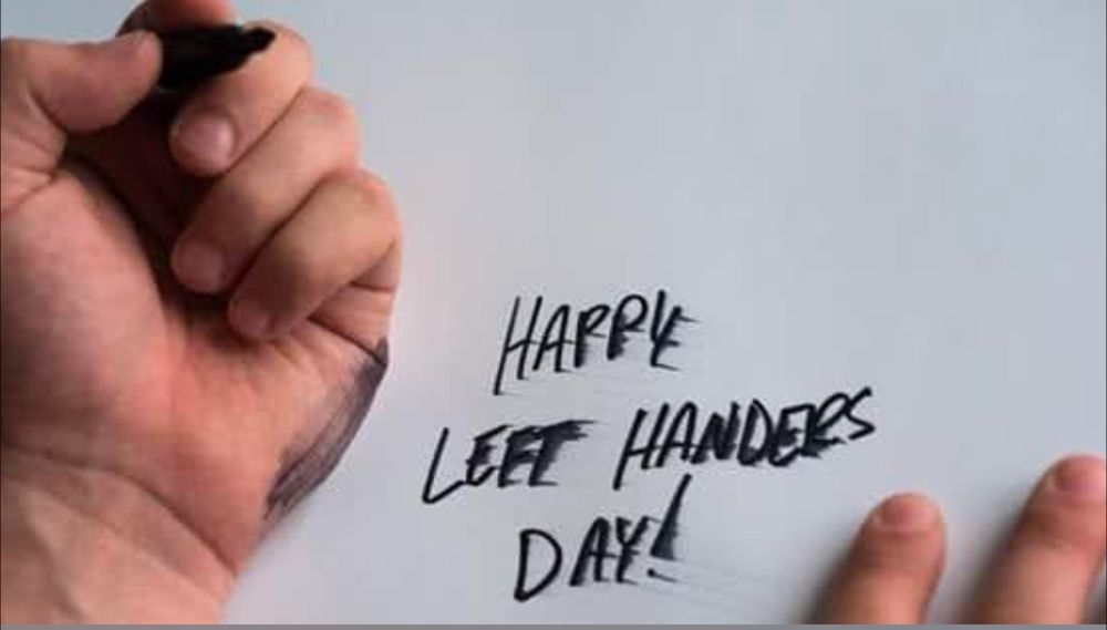 left handed person writing happy left handed day with the text smeared and marker on their hand