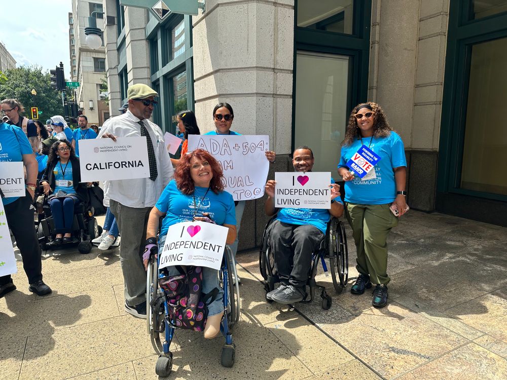 A picture taken around the same time as the first crowd photo. The Four Rolling Start representatives are together for a group photo, holding their support signs and smiling to the camera.