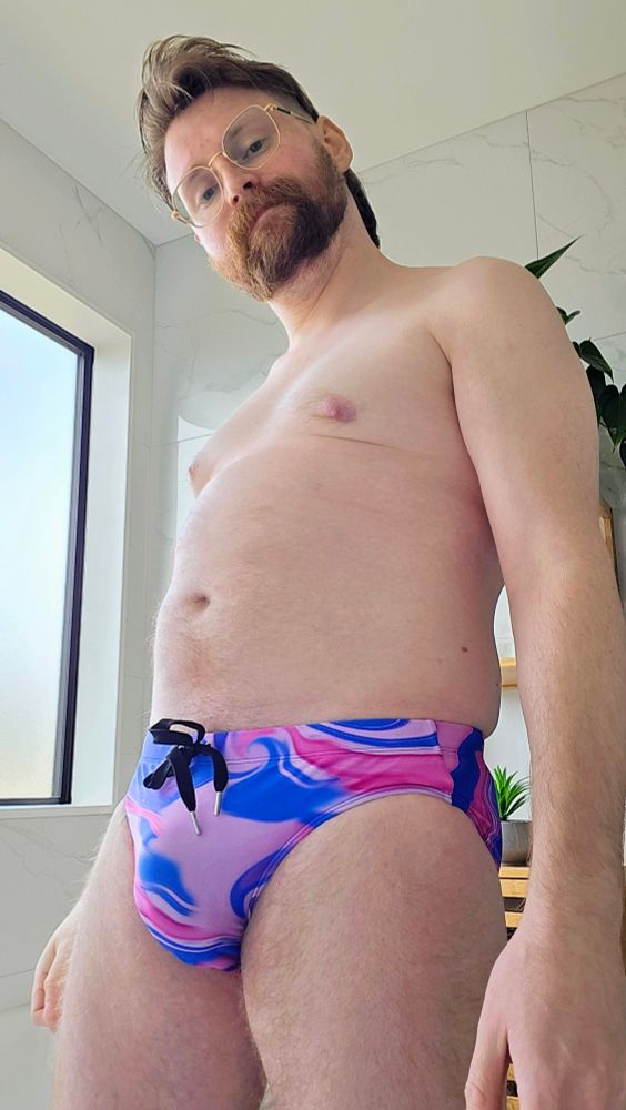 Tiz wearing a blue and pink swirly speedo with a black drawstring