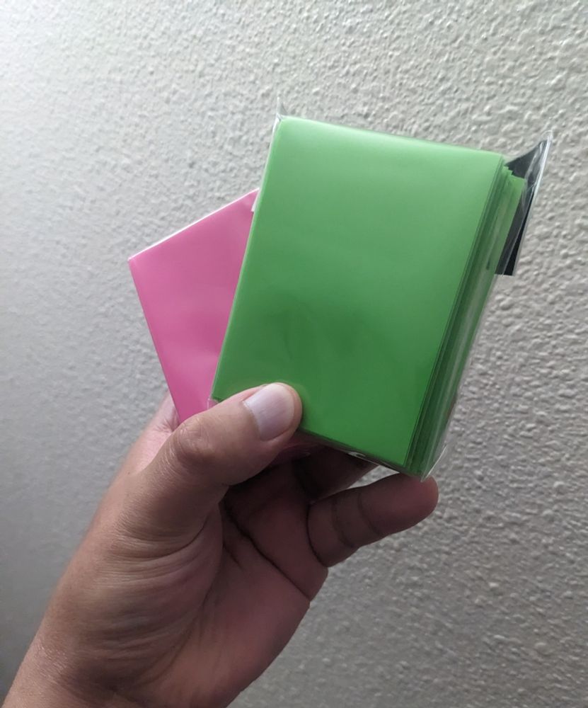 Two unopened packs of sleeves. One is lime green and the other is pink