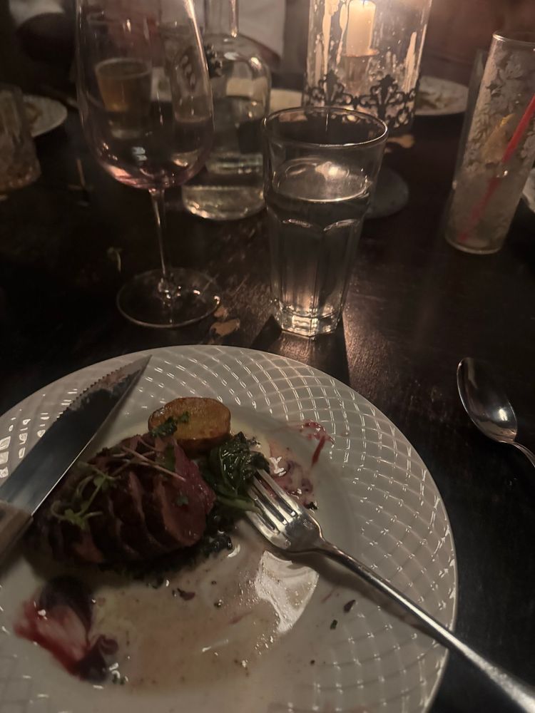 Dimly lit speakeasy restaurant with a plate of duck and potato 