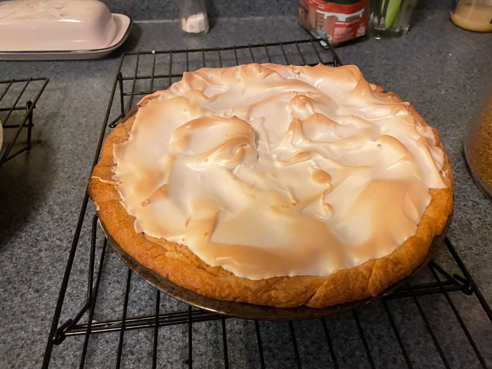 Chocolate meringue pie,  cooling on a black wire rack.