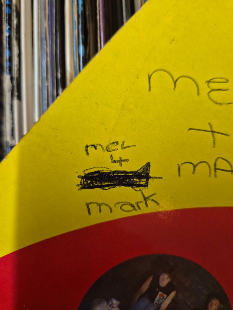 Writing on the back cover of a vinyl has Mel 4, then a scibbled out name and Mark written underneath.