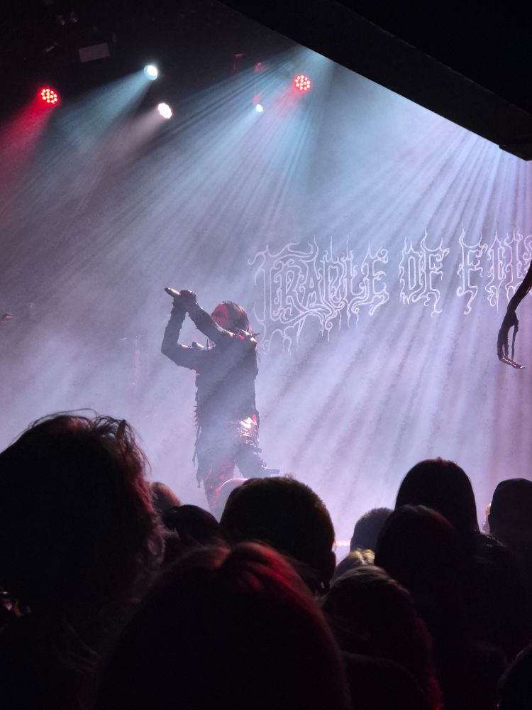 Dani Filth holds the microphone in both hands as he performs one of his trademark screeches.