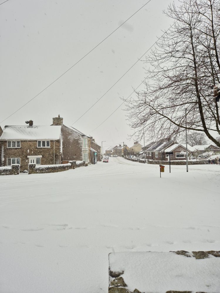 View down the main road through Kirk Merrington, taken from the village green. Snow covers every surface and it's almost impossible to tell where the roads are.