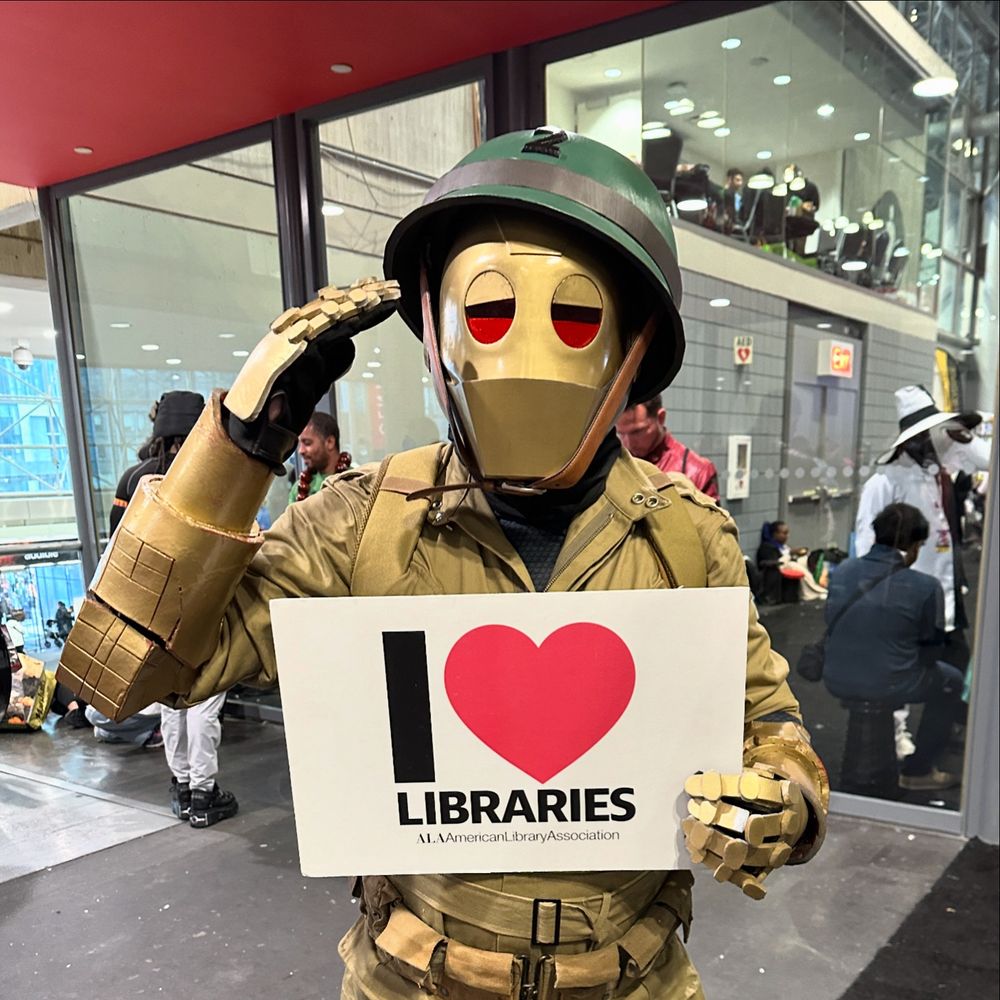 G.I. Robot saluting and holding a I love libraries sign 