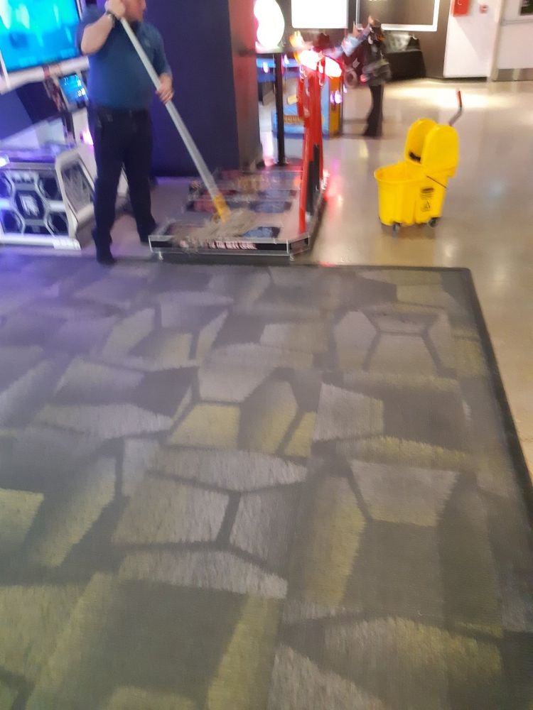 A blurry photo of an arcade employee mopping the Pump it Up dance pads.