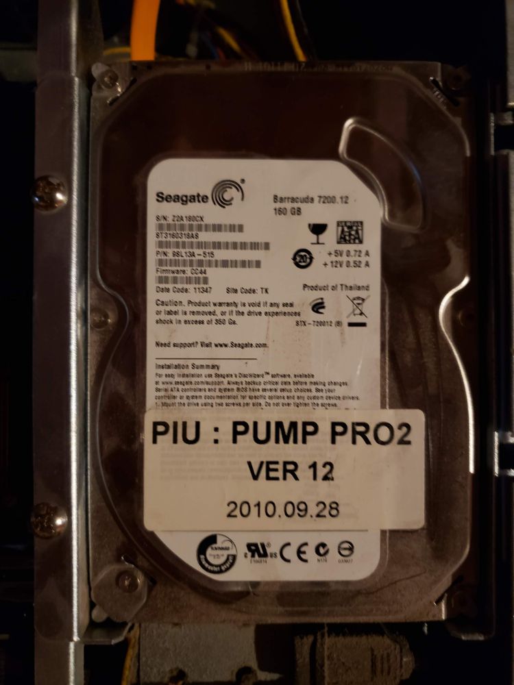 A photo of the HDD containing the game software. It's a Seagate Barracuda 160GB drive, with a large label stuck to it that says "PIU : PUMP PRO2
VER 12
2010.09.28"
The September date stamp marks this as a somewhat early copy, at only 3 months after the game's official release, with the typical availability window for Pump it Up games being 1-2 years.