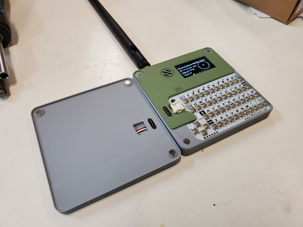 Surprise, the solar panel is a removable lid! In this photo, the lid is sitting on the table upside down, on the left of the main body. There are magnets in 3 of 4 corners. 

The main body, on the right side, is half covered with a green faceplate, containing a screen and speaker. There is a small white keyboard PCB on the bottom half.