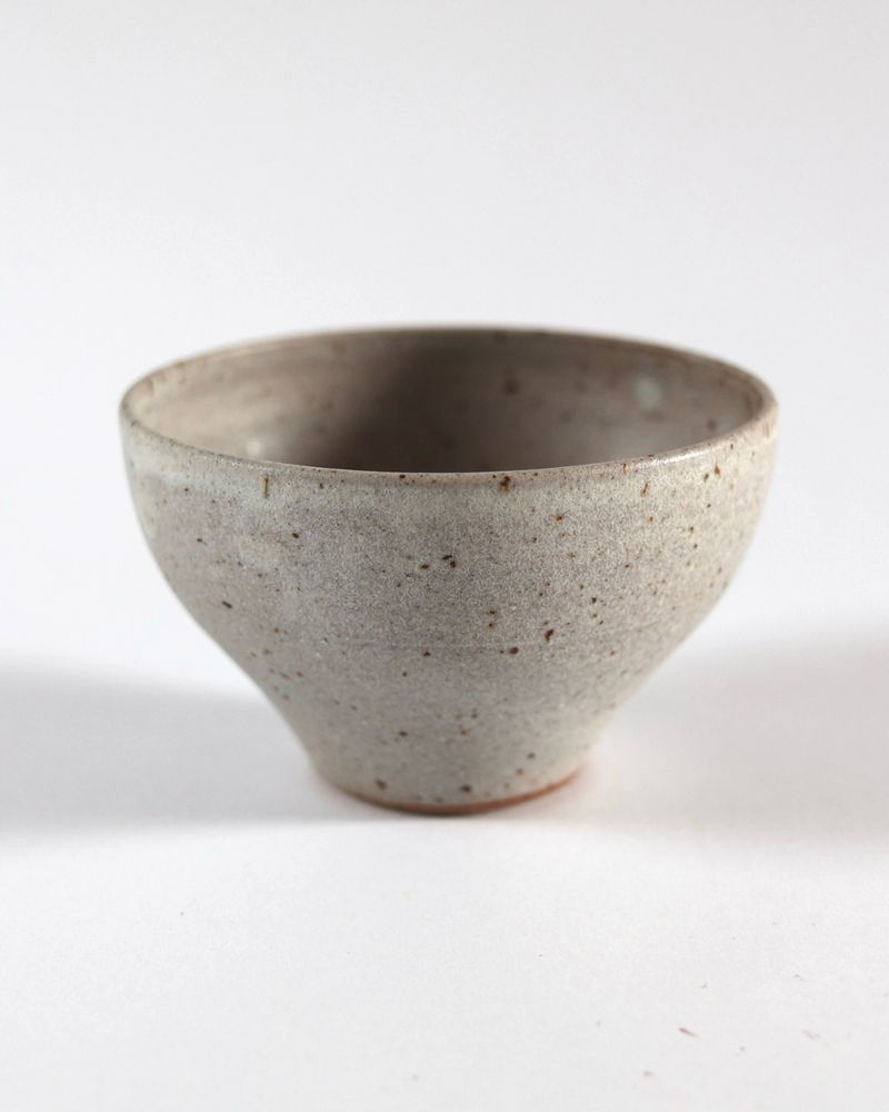 A small dip bowl glazed in warm gray, made from speckled buff clay