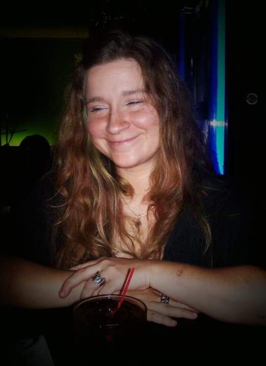 Me, 13 years ago. I just finished performing with my band, Midnite Bluz (I didn't name it, ok?)
My hair is long, naturally curly and wavy, red with green stripe. I have a coke in front of me
 My arms are crossed and I'm looking shyly away from the camera, with a smile.