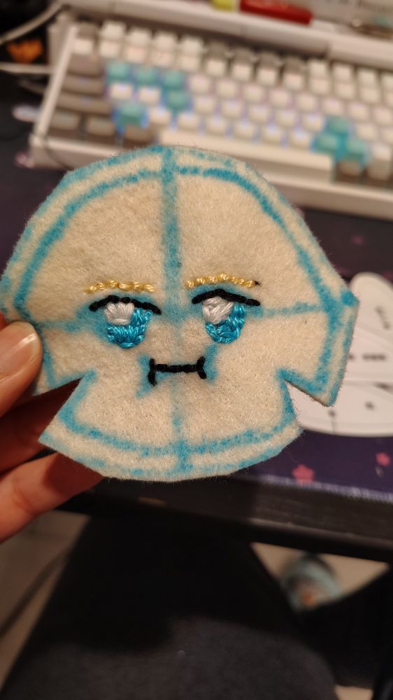 Circle shaped Felt with a face embroidered on to it