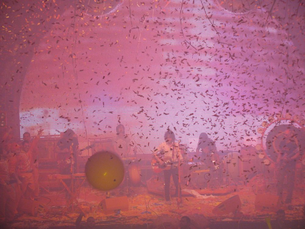 Le groupe Flaming Lips sur scène.  Il y a des confettis qui tombent sur le groupe et des ballons sur la scène. Tout est rose. Spectacle au Métropolis (maintenant MTELUS) à Montréal (juillet 2010)