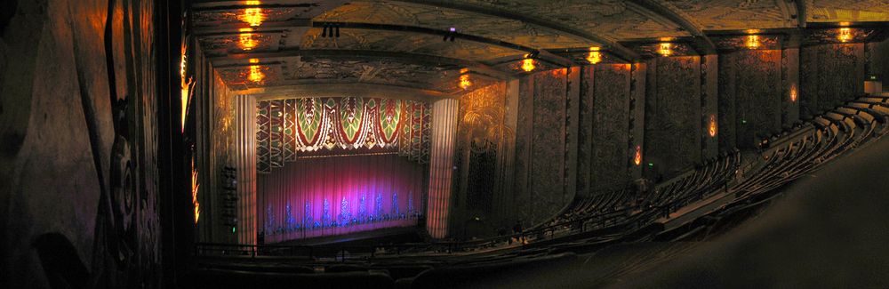 Paramount Theatre, Oakland: the theatre is a feast for the eyes even before the show starts. The curtain of purplish red and metallic blue, the amber lamps giving walls and seating a warm brown cast and extensive relief work that turns the space into an exquisitely carved cavern.