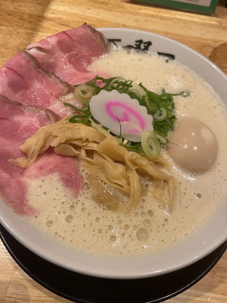 ラーメン。煮卵、メンマ、チャーシュー、ネギ、ナルトが乗っている。
