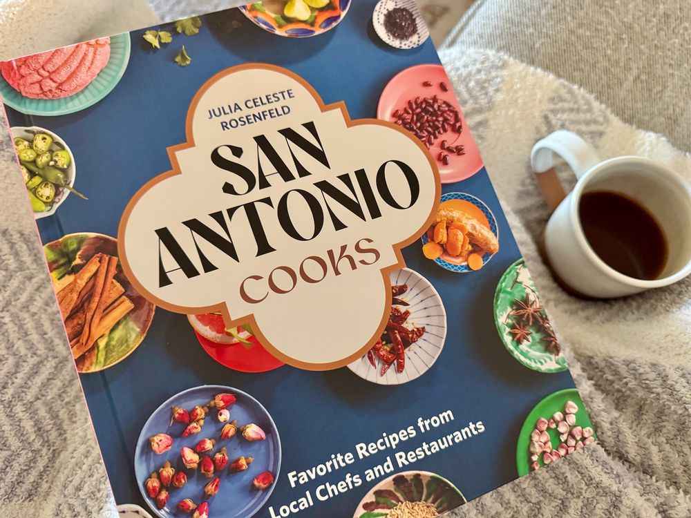 The cookbook, San Antonio Cooks, resting in my blanket covered lap next to my cup of coffee