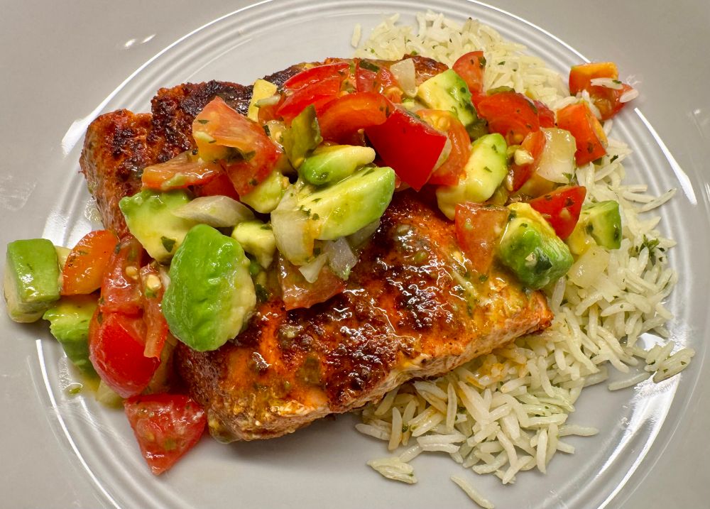 My plate with blackened salmon resting on steamed rice and topped with avocado pico