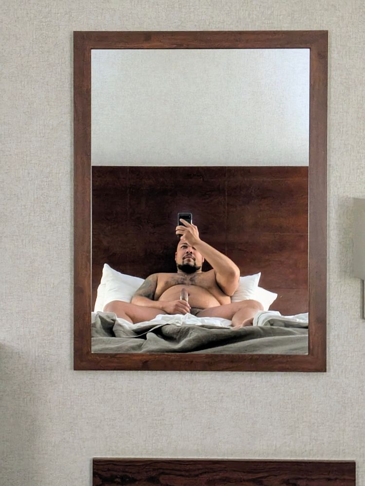 Photo of me through a mirror laying in bed holding my dick 