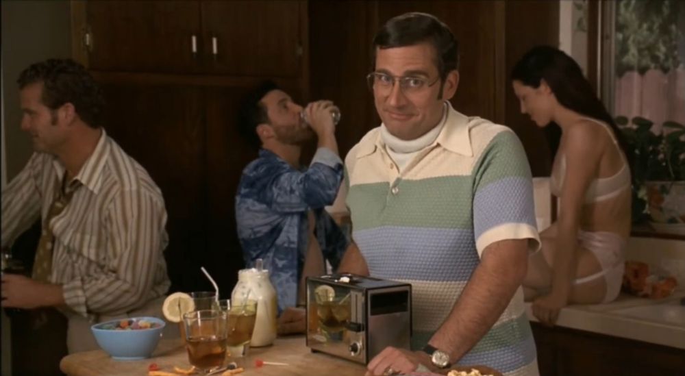 Steve Carrell as Brick Tamland in Anchorman. He is standing in a kitchen where a party is taking place. He just put mayonnaise in a toaster as he was introducing himself with a low IQ.