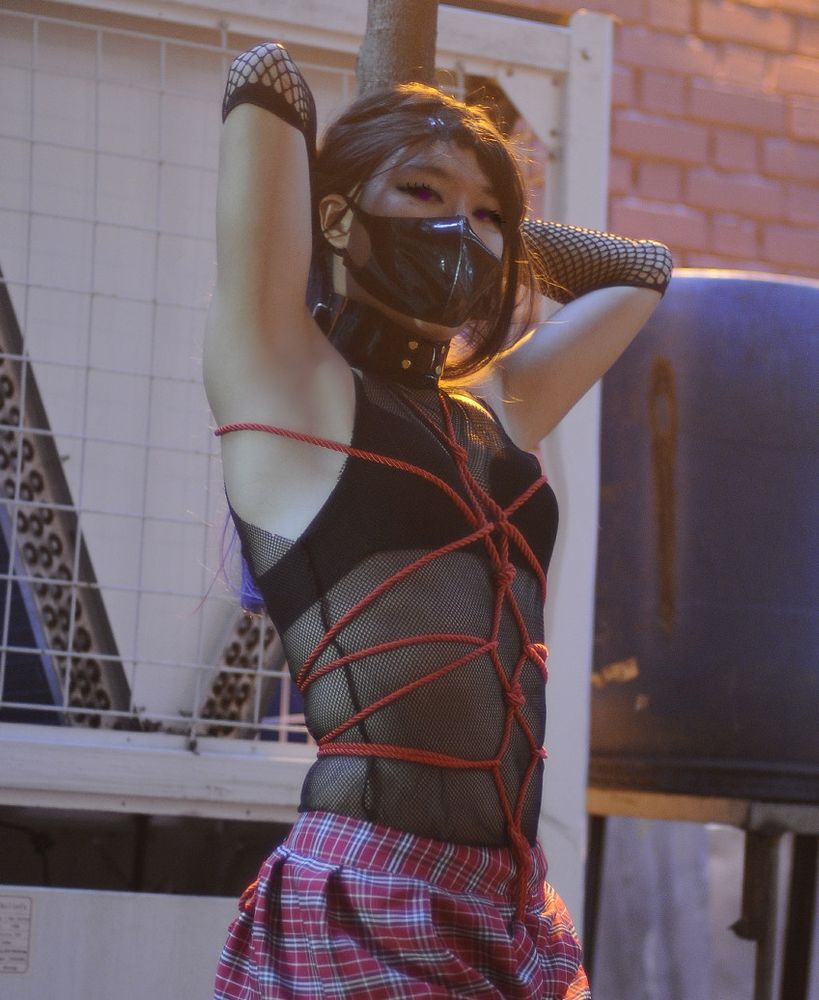 Me posing in front of a pole, with ropes tied around my body