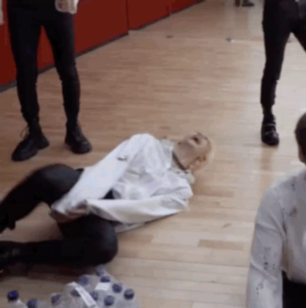 a man in a white shirt is laying on the floor in front of bottles of water