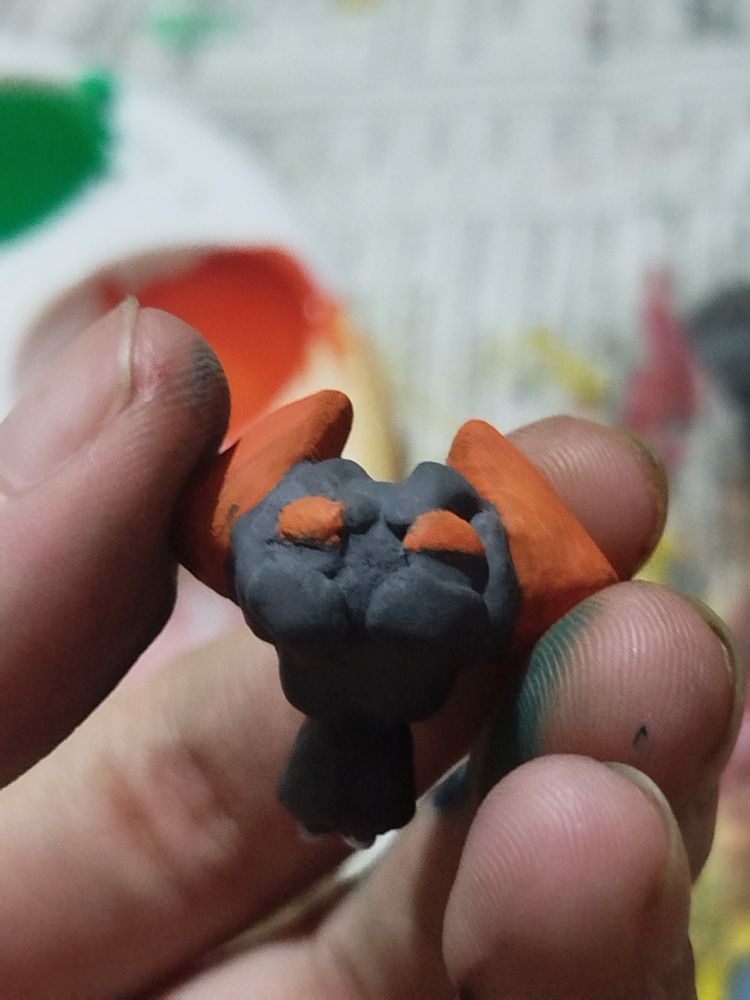 clay Biograft, named Tempura, held in paint stained fingers lovingly