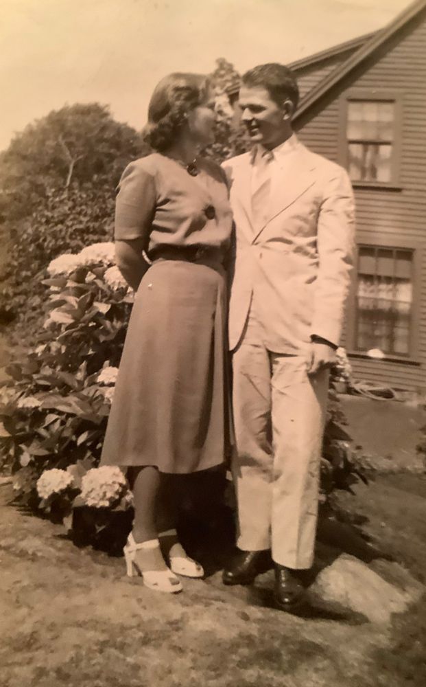 Sepia-toned photo, circa 1950, of a young couple in love, standing on a lawn by an old house, with flowers (Rhododendrons?) behind them. The woman wears a simple dress and pendant. The man wears a white suit. They will have four children, of which I am the youngest. 

The man will die at 59. The woman will never remarry. She turns 101 in September and is of sound mind. Her short term memory is just starting to fade slightly, but her long term memory is where he lives in full and will continue to do so...

He would have been 101 today.