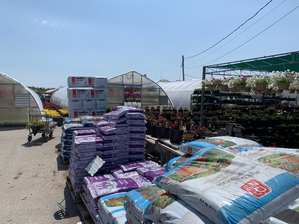 Stacks of soil bags. There are greenhouses in the back. 