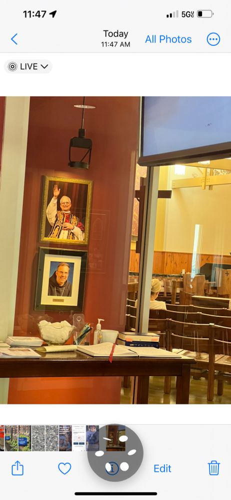 A photo of the foyer of the sanctuary of the Holy Spirit Parish at the Newman Center at the University of Kentucky shows framed photo portraits of Pope Leo and Lexington Bishop Father John Stowe. Through glass, chairs in rows and large candles are seen in the modern architecture church where hundreds of Catholics attended the Feast Day Mass celebrating the Solemnity of the Assumption of Mary. Father Anthony was the celebrant fir the 12:10 pm Mass. 