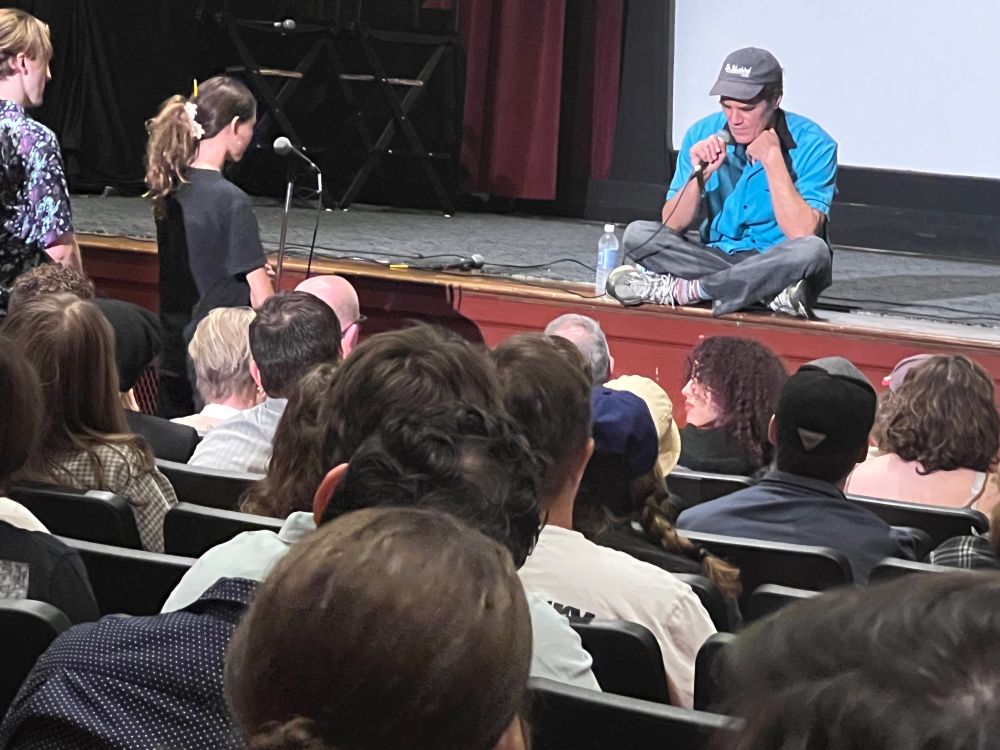 Actor Michael Shannon does a Q &A on Directing at the 12 Lions Film Festival at the Kentucky Theater in Lexington, KY. Shannon, in a blue baseball cap, turquoise bowling shirt and jeans, sits on the edge of the stage as his questioner, an 8th grade girl in a black Dragonslayer t-shirt a ponytail in a white scrunchie.