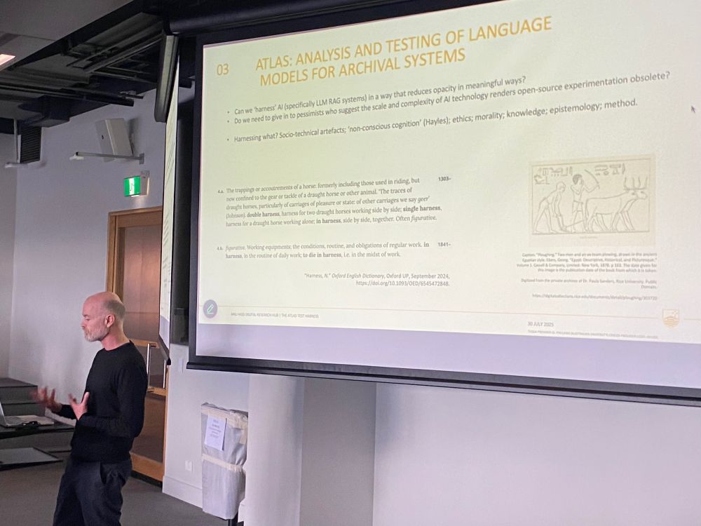 Man at lectern with a slide in background detailing ATLAS: Analysis and testing of language models for archival systems, with linked discussion on the historical linguistics and socio-cultural uses of the term “harness”
