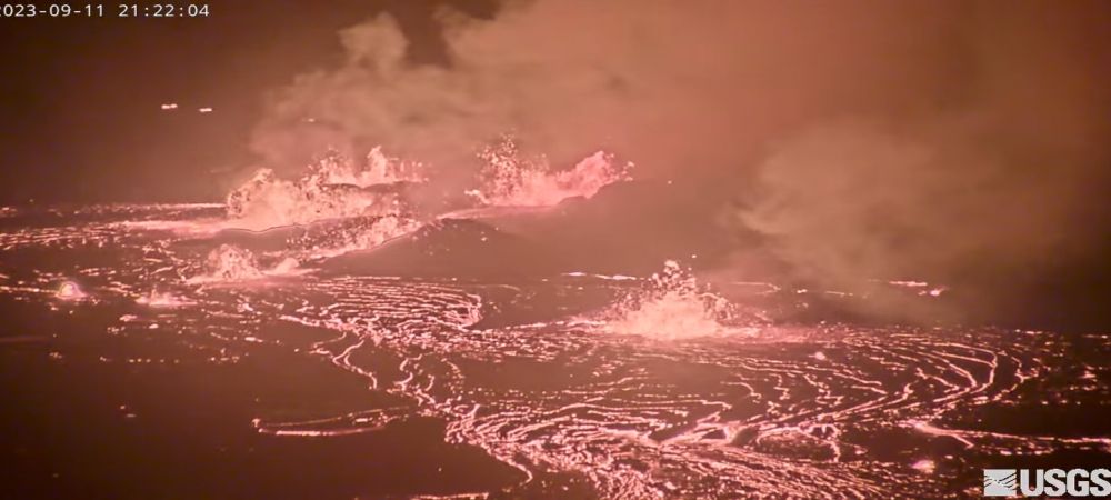 A screen shot of the Kīlauea eruption live feed, showing fire fountaining of glowing red lava from multiple vents feeding flows of red glowing lava at night