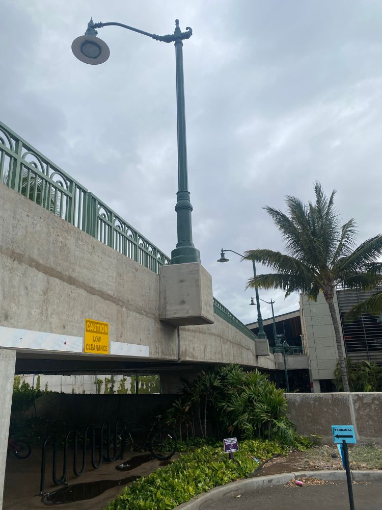 Overhead streetlight bases attached to the side of a ramp bridge instead of sitting on the ground.