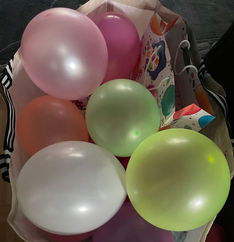 Zu sehen ist eine Tasche mit sechs bunten, aufgepumpten Luftballons. 