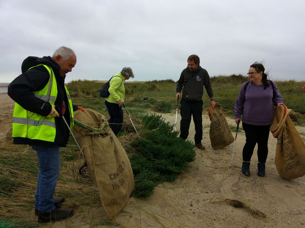 Four people collecting litter from the beach at Gibraltar Point National Nature Reserve