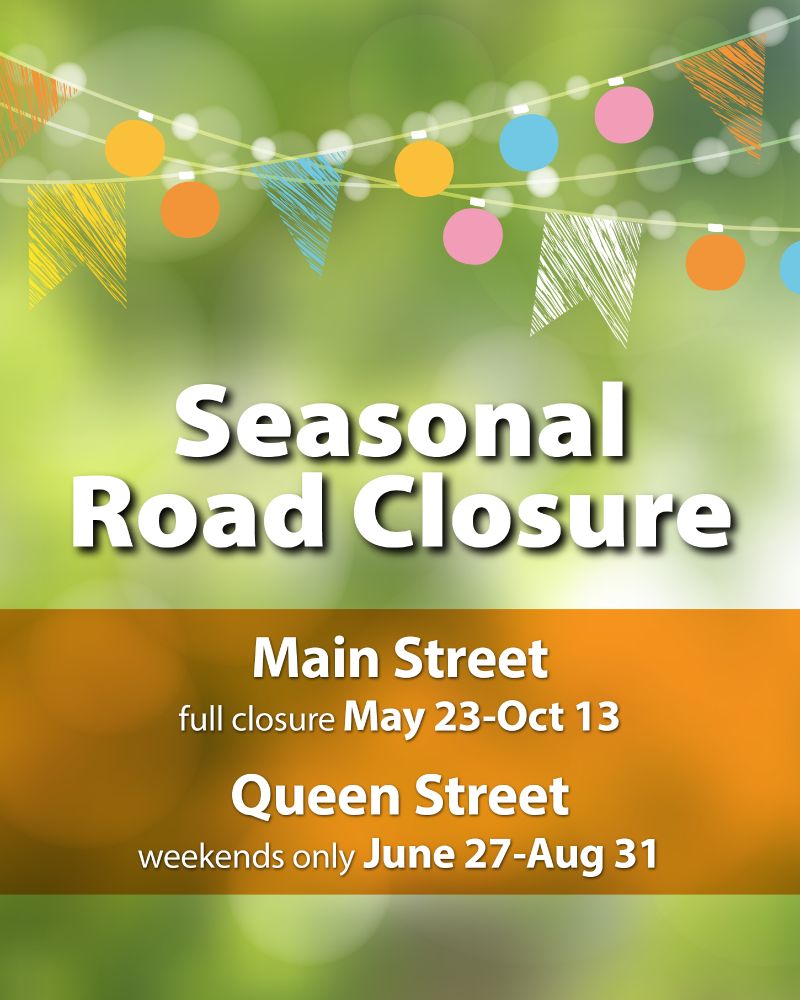 Poster announcing Seasonal Road Closures on Main Street from May 23 to October 13 and on Queen Street weekends only June 27 to August 31. The background features decorative lights and colorful banners against a blurred green setting.