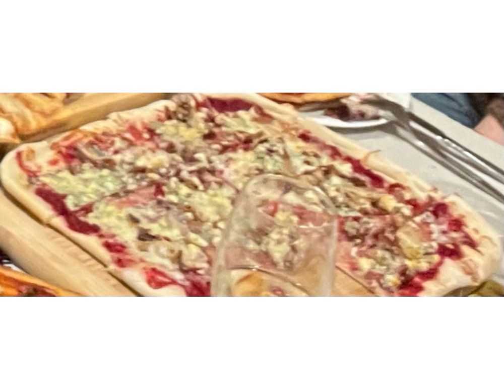 Pizza with orange-cranberry sauce, turkey, gorgonzola cheese, and pecans and a glass of wine next to it