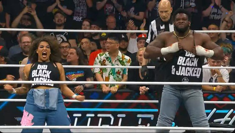 Image of Willow and Hobbs standing in an AEW ring posing with shirts that say "Big, Black, & Jacked" 
