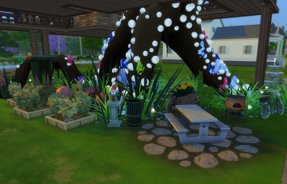 The garden and patio space of the treehouse. 3 planters are on the left with a picnic table, grill, and trashcan on the right. Also visible is a bike off to the front. 